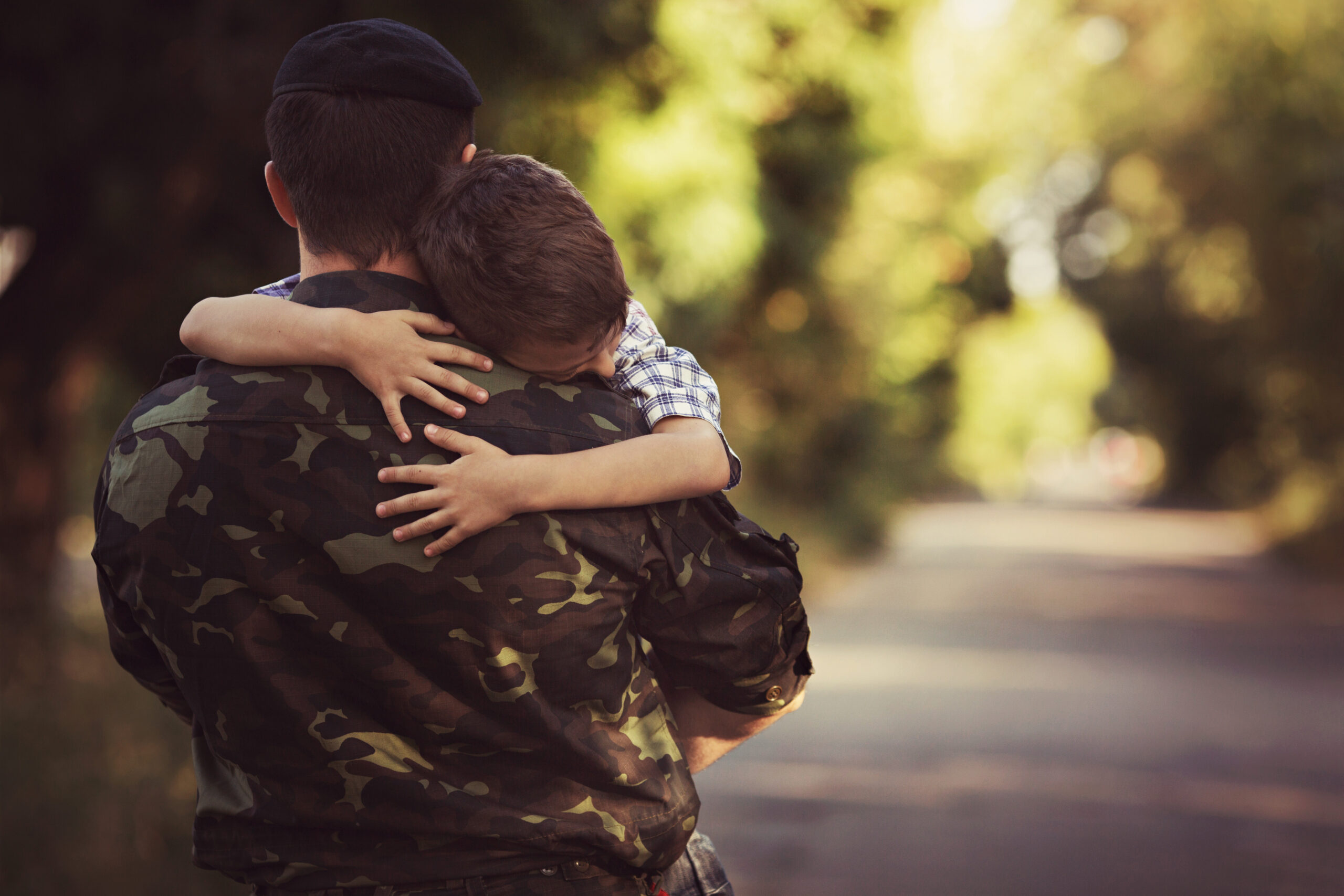  A young boy and a military man hugging each other. 