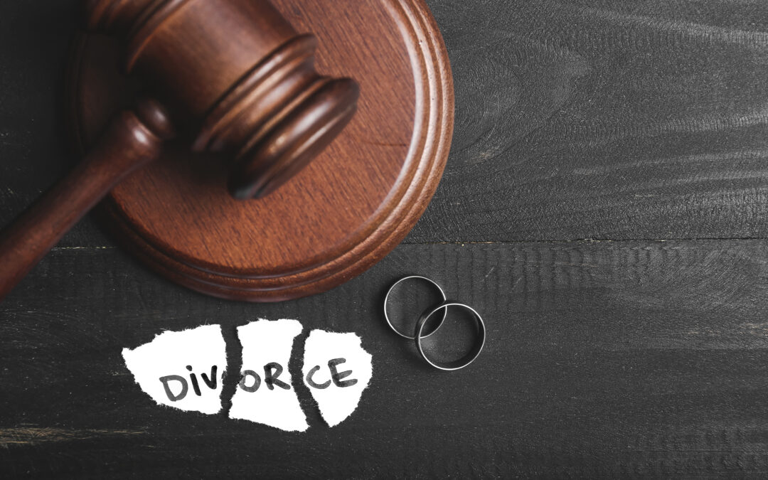 Judge's gavel, rings, and torn paper with the word divorce