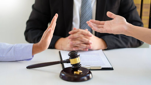 The hands of two arguing spouses while their lawyer sits in the middle with some notes and a gavel